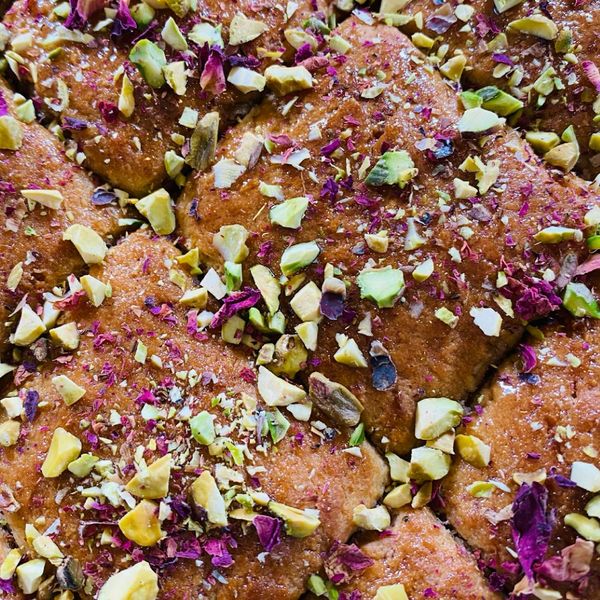 La Harisa es un pastel tradicional muy popular en distintas regiones del Medio Oriente, también conocido como Basbousa en Egipto o Namoura en Líbano. Se prepara con sémola, yogur y ghee, lo que le da una textura suave por dentro y ligeramente crujiente por fuera. En esta versión, el coco rallado, el cardamomo y los pétalos de rosa lo convierten en un postre fragante, elegante y especial. El proceso es sencillo: se mezcla la masa, se corta antes de hornear en cuadros o diamantes y al salir del horno, se baña con un chorrito de jarabe de azúcar que aquí reemplazamos por endulzantes no refinados como jarabe de maple. Cada pieza se adorna con un pistache o almendra, lo que le da un contraste crujiente. Servido tibio con un té de canela, resulta un postre reconfortante, cargado de tradición y aromas que evocan hospitalidad y celebración. Es ideal para otoño e invierno o para ocasiones especiales en las que se busca un postre cálido, especiado y nutritivo.