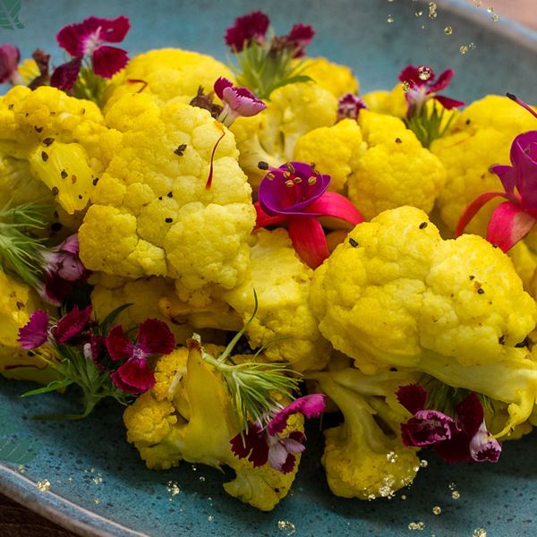 Esta es una de esas recetas que aprendí cuando me mudé a Barcelona a los 23 años para hacer mi máster y me sorprendió descubrir lo versátil que puede ser la coliflor: una verdura que se transforma de tantas maneras distintas según cómo se prepare. La coliflor, al dorarse ligeramente, desarrolla un sabor más profundo, dulce y reconfortante. En esta receta, el azafrán que es una de las especias más valiosas del mundo, en Ayurveda se considera rasayana, es decir, rejuvenecedor. Nutre la piel, favorece la claridad de la mente y fortalece los tejidos reproductivos, además de apoyar la digestión suave gracias a su cualidad ligera y aromática. Se combina con cúrcuma y comino para darle un carácter cálido, aromático y equilibrado. El resultado es una preparación que aunque es sencilla, se siente especial: la coliflor queda tierna por dentro, dorada por fuera e impregnada de un líquido dorado y fragante que la vuelve elegante y digestiva. El toque final de limón realza los sabores y aporta frescura. Es ideal en otoño e invierno, cuando el cuerpo agradece platos tibios, especiados y ligeros que nutren sin pesadez. Puede servirse como guarnición junto a un grano o verdura que construye, acompañado de legumbres o proteína animal para formar una comida completa.