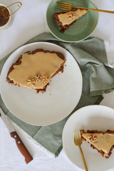 Nunca se me va a olvidar el olor y el sabor del pastel de zanahoria de mi mamá. Era sencillo, pero tan fragante, tan satisfactorio y reconfortante. ¿Tenía buttercream, crema de queso o un frosting encima? Nope, nunca. Eso no existía en mi casa. Yo no crecí amando el frosting dulce, simplemente aprendí a apreciar la zanahoria por lo que es: una verdura con dulzor natural y textura suave. Esta es mi versión ayurvédica del clásico carrot cake: más ligera, nutritiva y fácil de digerir. La harina de espelta lo hace menos pesado que la de trigo común, mientras que el puré de manzana mantiene la humedad sin necesidad de exceso de grasa. Las especias: canela, cardamomo y nuez moscada aportan calidez y lo vuelven más digestivo, mientras que las nueces de castilla le dan un contraste crujiente y mineralizante. El resultado es un pastel fragante y equilibrado, que se disfruta tanto en el desayuno ligero como de postre o snack acompañado de un té especiado por la tarde. El frosting que hice es una mezcla cremosa de tahini con maple y un toque de limón: ligeramente ácido, con notas de nuez y sin el exceso de azúcar de los glaseados tradicionales. Aporta frescura y cremosidad, pero sin robarle protagonismo al pastel. Es ideal para otoño e invierno, cuando el cuerpo agradece postres especiados, tibios y nutritivos.
