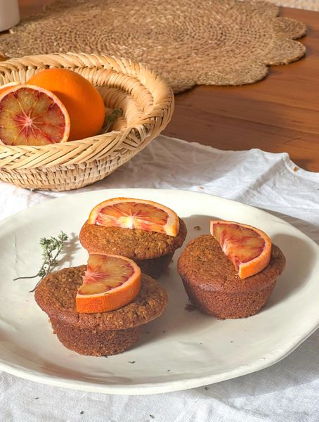 Estos muffins son una forma deliciosa y fragante de disfrutar la naranja en todo su esplendor. La combinación de harinas de espelta (o de avena) y almendra les da una textura esponjosa pero saciante, mientras que la ralladura y el jugo fresco de naranja aportan un dulzor natural y un aroma cítrico que llena la cocina al hornearse. Las especias, cardamomo e hinojo, equilibran el frescor de la naranja con calidez y notas digestivas, creando un muffin ligero pero al mismo tiempo nutritivo y especial. El ghee o aceite de oliva añade la untuosidad necesaria para que se derritan en la boca sin necesidad de coberturas extra. Funcionan como desayuno rápido acompañados de una infusión ligera, o como un snack a media tarde. También se disfrutan muy bien como postre sencillo. Es ideal en otoño e invierno, cuando el cuerpo agradece postres ligeros pero aromáticos que elevan el ánimo sin dejar pesadez.