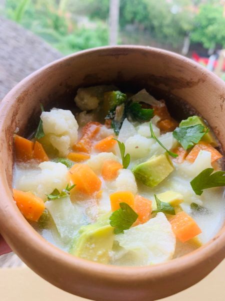 Amo el ceviche y quería encontrar una manera de hacerlo vegetariano y a la vez más digerible. Los ceviches tradicionales suelen llevar muchos elementos crudos que aunque sabrosos, pueden ser difíciles de procesar. Así nació esta receta: fresca, sabrosa y ligera, pero mucho más amable con la digestión gracias a que las verduras se blanquean ligeramente. La leche de tigre a base de leche de coco, limón, algas y especias es la clave: cremosa, cítrica y mineralizante, con un toque herbal de cilantro y la frescura del jengibre. La coliflor y la zanahoria, al estar cocidas al dente, mantienen su textura sin ser pesadas mientras que el aguacate aporta suavidad y saciedad. Es ideal en verano y primavera, cuando el cuerpo agradece platos frescos, vibrantes y ligeros. Puede servirse como entrada o como parte de la porción de los dos tipos de verduras en una comida completa. Y si lo prefieres también puedes añadir pescado fresco para transformarlo en un ceviche tradicional, pero más equilibrado.