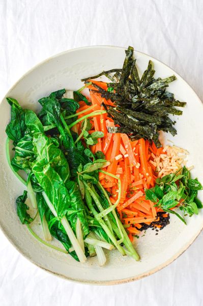 Una ensalada nutritiva y con un carácter asiático gracias al aceite de ajonjolí, el tamari y el toque fresco de la menta. El bok choy, de sabor ligeramente amargo y rico en minerales, se combina con la dulzura de la zanahoria y la profundidad mineral de las algas. Estas, además de aportar un sabor único, son una excelente fuente de yodo y oligoelementos que apoyan el metabolismo y benefician la función de la tiroides. El jengibre y el comino negro apoyan la digestión y estimulan la circulación. Puede servirse sola o como la parte de verduras que purifican y que construyen dentro de una comida completa, acompañada de quinoa y legumbres, o incluso con noodles de arroz y pescado a la plancha. Es ideal en primavera y verano, cuando el cuerpo agradece preparaciones frescas, ligeras y con un toque especiado que mantenga el fuego digestivo activo sin sobrecargar.