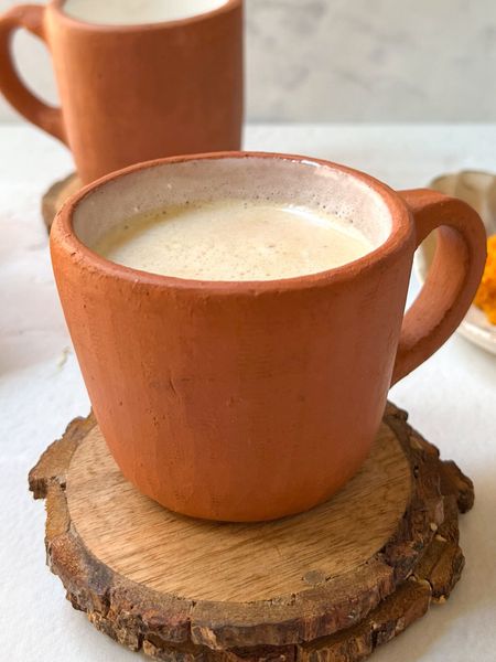 Una bebida cálida y reconfortante que calma el sistema nervioso y prepara al cuerpo para un descanso profundo. Inspirada en las recetas tradicionales ayurvédicas para equilibrar Vata dosha, combina leche tibia con especias que relajan, nutren y estabilizan la mente antes de dormir. La nuez moscada es un sedante natural suave. Rallarla justo antes de usarla permite conservar sus propiedades y potenciar sus efectos, ya que el polvo comercial suele perder gran parte de su valor medicinal. La canela mejora la circulación y da calidez y el jengibre o hinojo equilibran la digestión nocturna para evitar sensación de pesadez. El ghee y el dátil añaden dulzor natural y un efecto nutritivo que sostiene el sistema nervioso y hormonal durante el sueño. Es una bebida que yo misma utilicé en las primeras semanas del posparto, cuando el cuerpo y la mente están más sensibles. Me ayudó a relajarme, calmar la mente y dormir mejor, incluso en noches cortas o interrumpidas. Ideal para noches frías o épocas de mucho movimiento mental, cuando el cuerpo necesita calmarse antes de descansar.