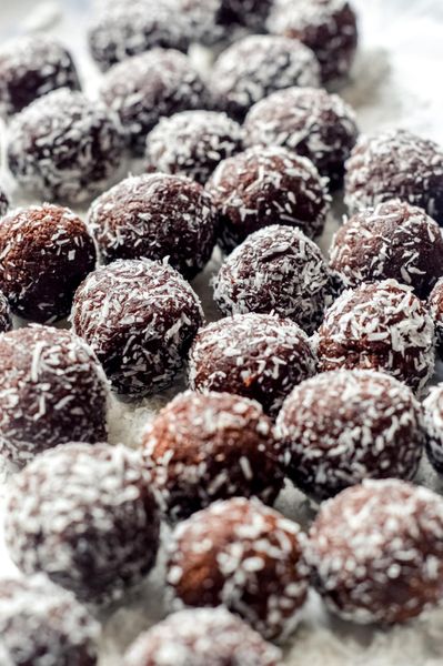 Estas trufas nacen de un recuerdo muy querido. Cada Navidad, mi mamá preparaba unas bolitas de chocolate inspiradas en el famoso Lazy Cake. La mezcla era irresistible, leche condensada, mucha mantequilla, galletas maría y luego las pasaba por coco rallado. Para mí, esas bolitas eran sinónimo de celebración, de casa y de infancia. Con los años, y después de estudiar más sobre nutrición y Ayurveda, quise recrearlas… pero de una forma que mantuviera la esencia sin el peso y sin la indigestión del original. Estas son mi versión ayurvédica: más ligeras, más nutritivas y profundamente más digestivas. Son más digestibles que las tradicionales porque tostamos la harina de avena, lo que las vuelve más ligeras y suaves para el estómago, también porque cocinamos los dátiles en ghee, haciéndolos más untuosos, cálidos y fáciles de asimilar, y porque las especias digestivas, cardamomo y canela, equilibran la dulzura natural y evitan pesadez. Además de que no llevan lácteos pesados ni azúcares refinados. El resultado es una trufa suave, aromática y reconfortante: dulce sin empalagar, nutritiva sin ser pesada, perfecta como snack, postre o para compartir después de una comida sin provocar indigestión. Puedes servirlas como parte de una mesa navideña, como un detalle saludable para visitas, o como ese antojo dulce que acompaña el té de la tarde sin inflamación ni culpa. Un homenaje a mi infancia… pero con el toque de Ayurveda, digestión ligera y nutrición real.